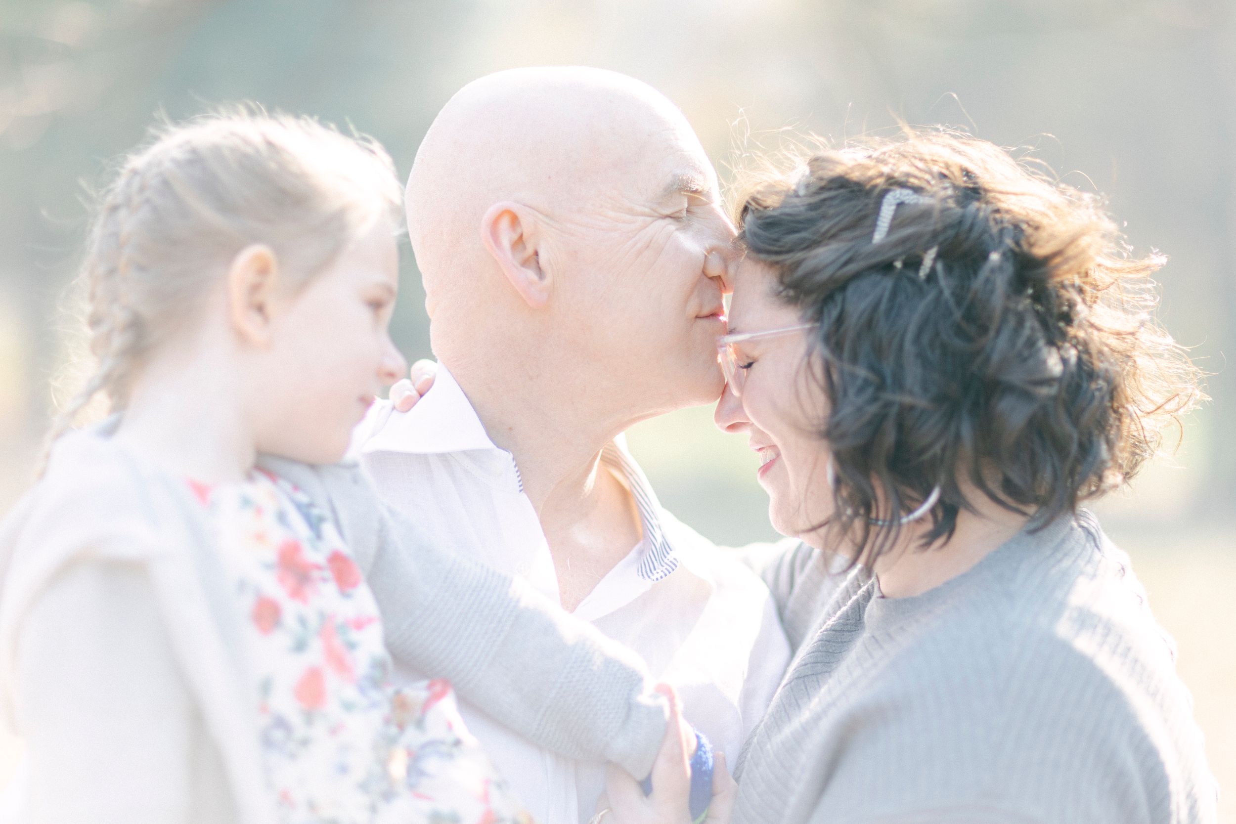 A tender family moment captured in soft dreamy light showing warmth and connection between three people.