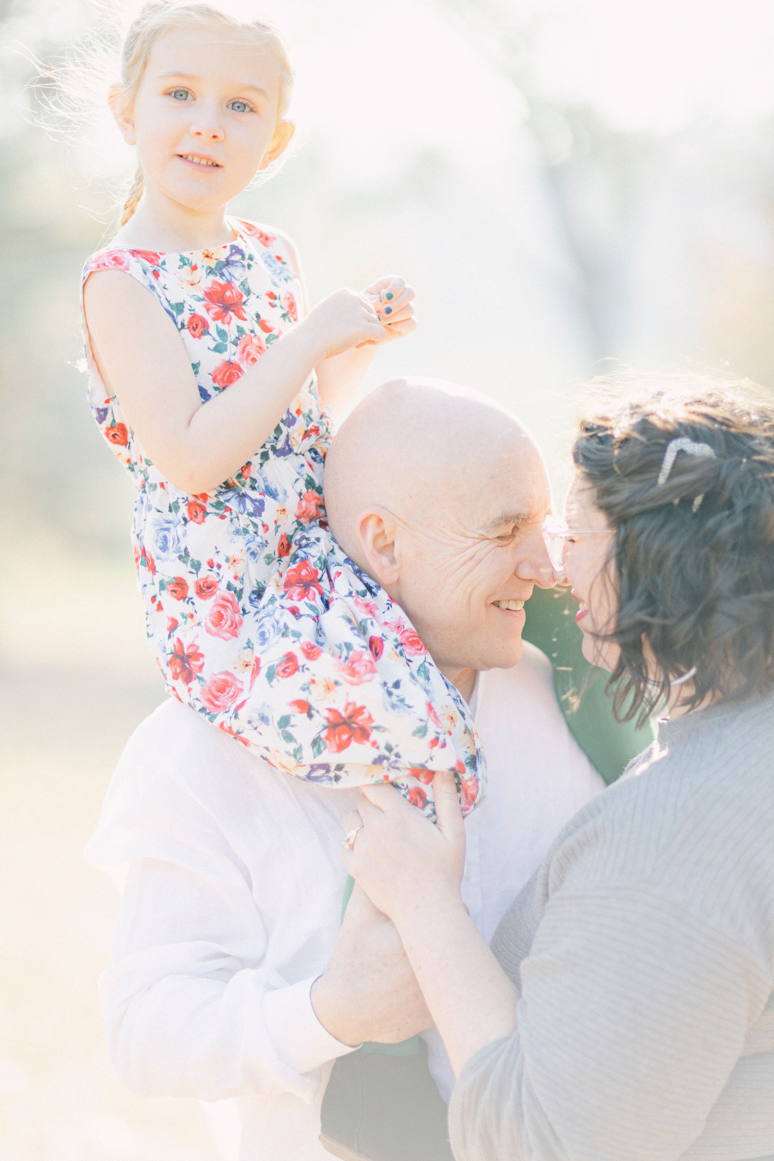 A playful family moment outdoors with someone in a floral dress being lifted up.