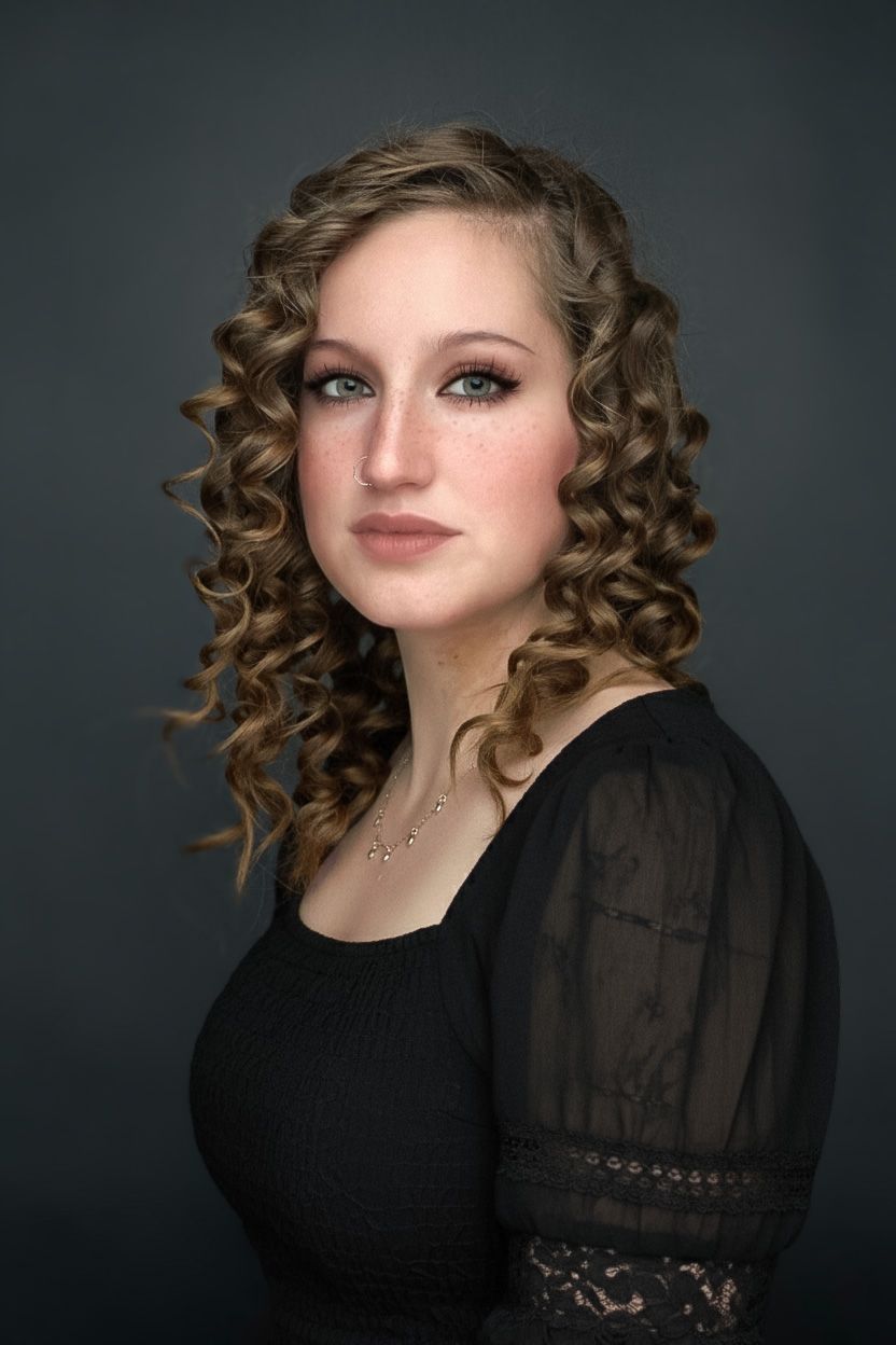 Glamour portrait with dramatic lighting features curled blonde hair, black sheer sleeve top and professional makeup.