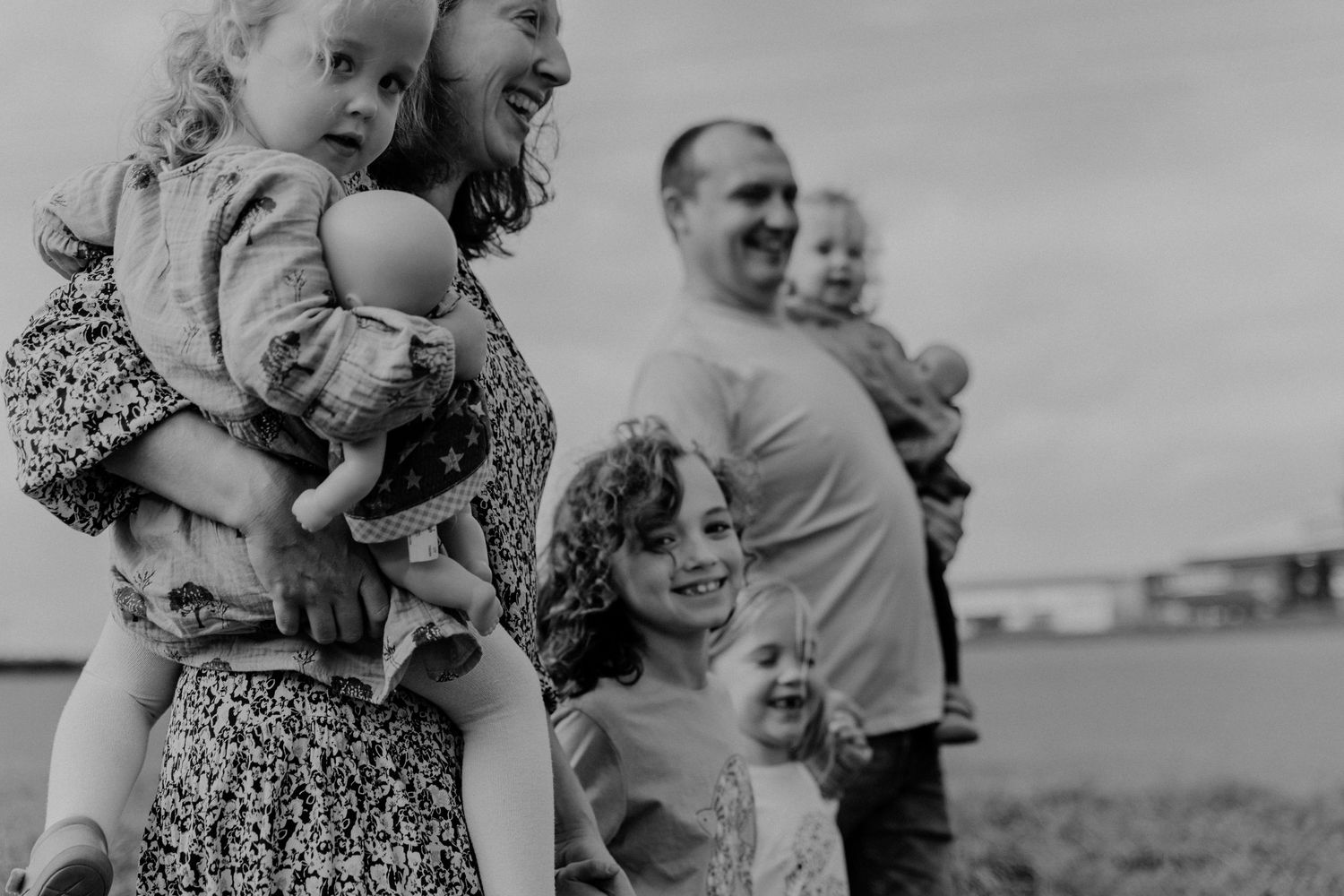 A family stands together outdoors in black and white, with young children and parents enjoying a moment in nature.