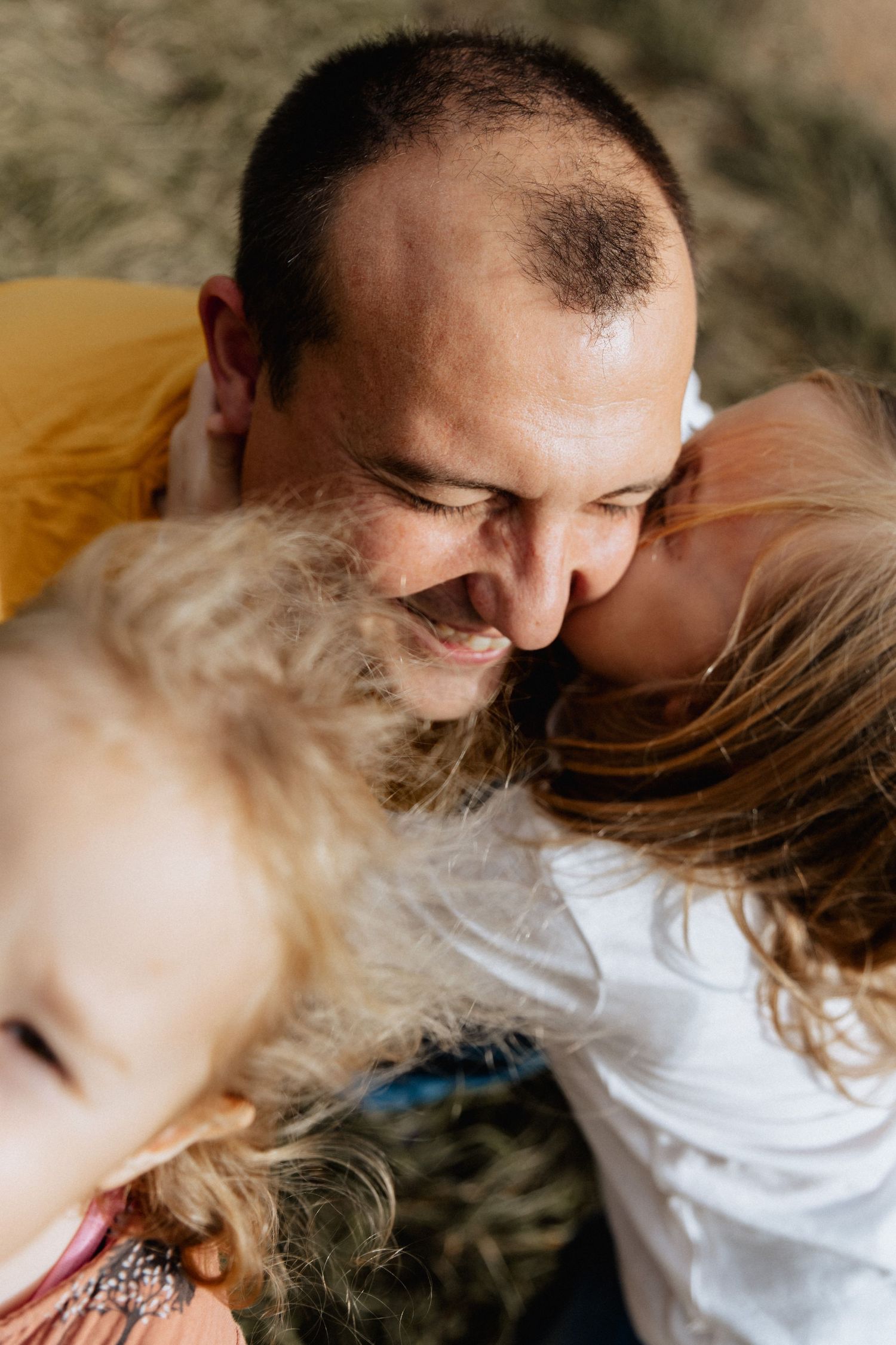 Close-up candid moment of a family sharing joyful laughter together outdoors on a sunny day.