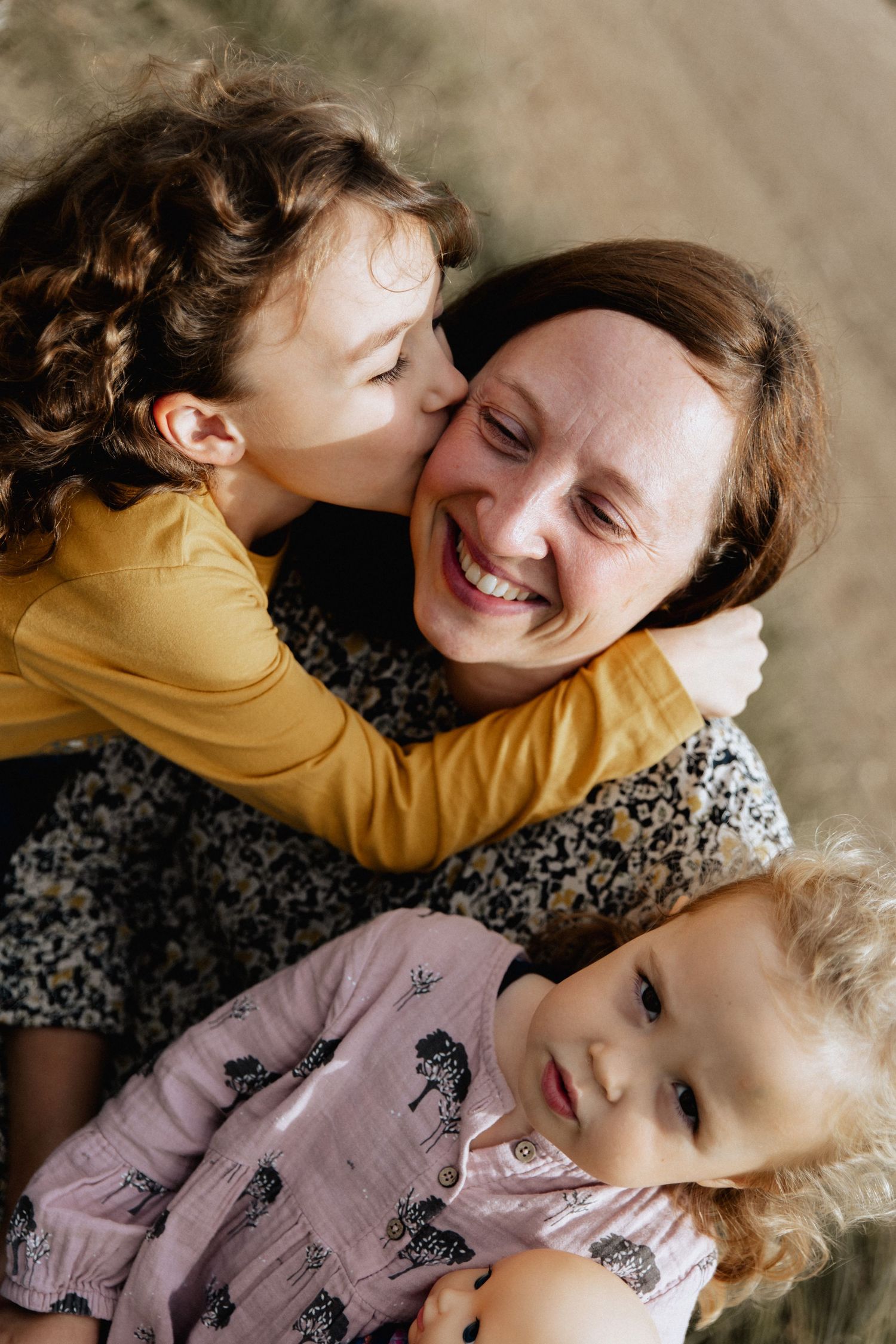 A warm joyful candid moment captured between a parent and children wearing yellow and pink outfits.