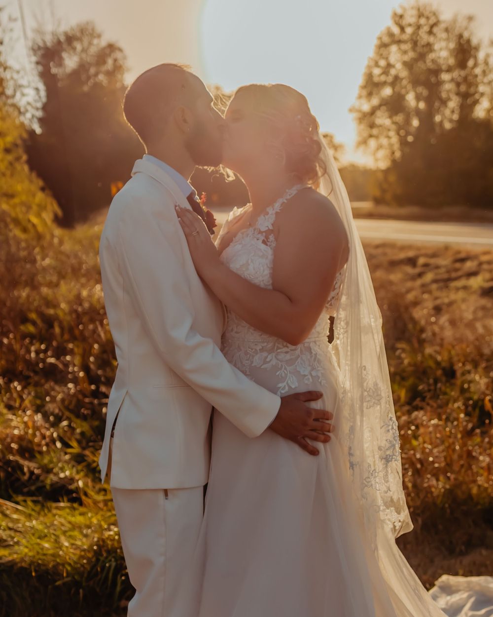 Intimate wedding portrait of couple embracing during golden hour sunset.