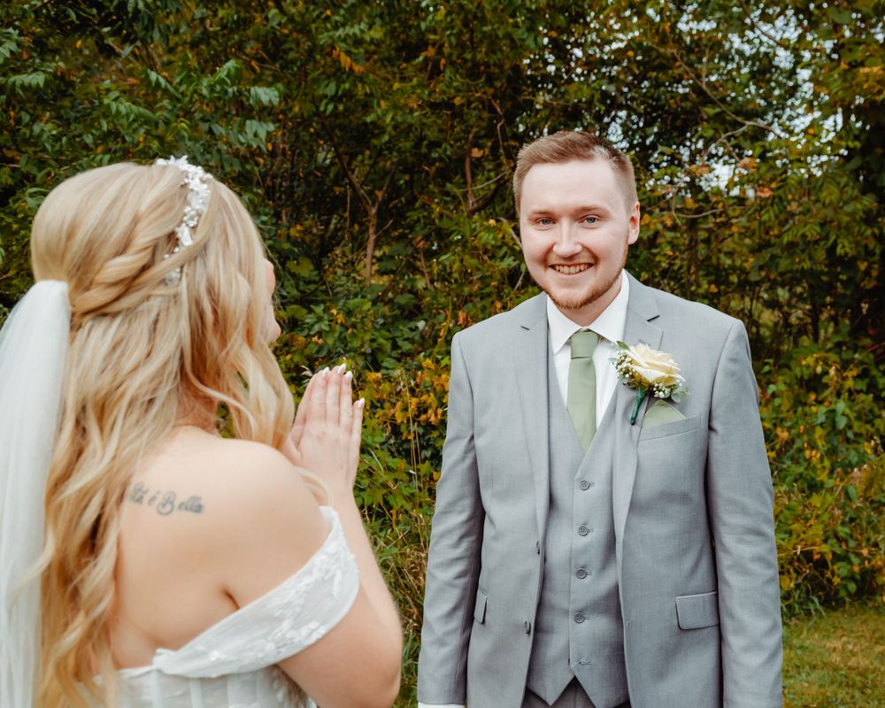 First look wedding moment captured in garden setting with autumn foliage.
