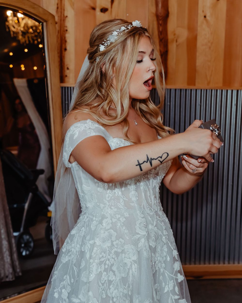 Bride in lace dress and crystal hairpiece checks watch during wedding reception.