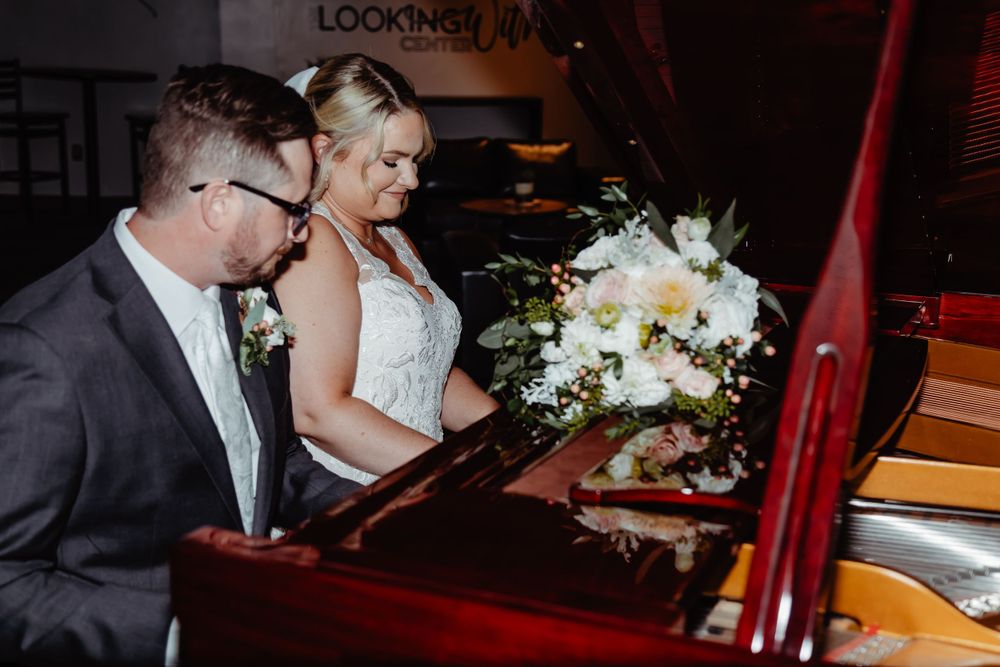 A couple sharing an intimate moment at a grand piano during their wedding celebration.