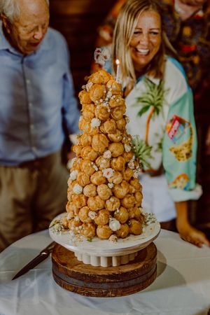 A spectacular croquembouche tower of golden pastry balls displayed on a white pedestal cake stand.