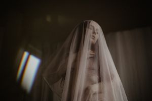 Ethereal figure draped in white veil creates ghostly atmosphere indoors.