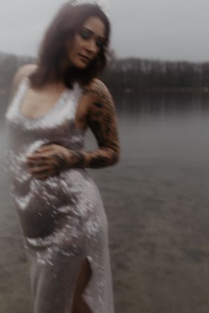 A dreamy portrait in a silvery dress against a misty lake backdrop.