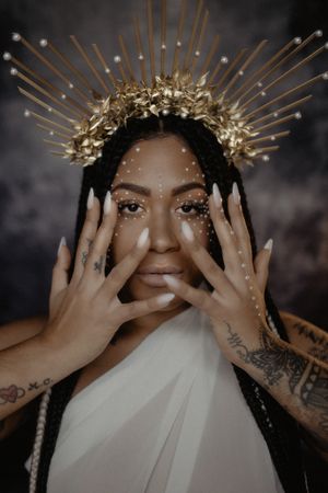 Portrait featuring an ornate golden crown headpiece with dramatic lighting and hand poses.