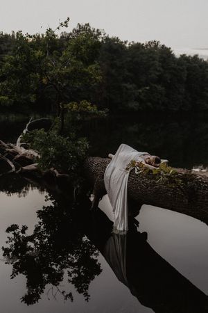 White fabric draped over fallen log above reflective lake water at dusk.