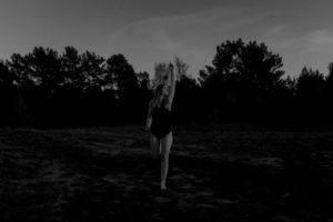 Schwarz-weiße Silhouette einer Person, die in der Abenddämmerung auf einem Feld steht.