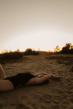 Liegende Figur am Sandstrand in der goldenen Stunde.