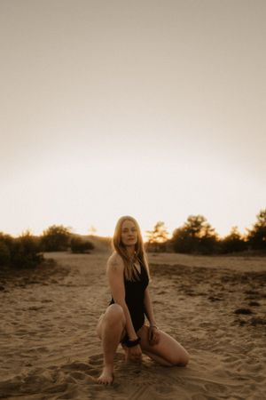 Die Figur posiert im Sonnenuntergang auf sandigem Boden in warmen Farbtönen.
