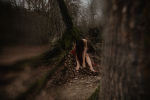 Artistic forest photography with focus on feet near mossy tree trunk.