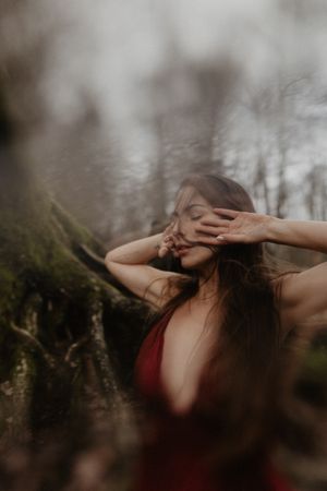 Artistic portrait in a forest setting capturing intimacy and emotion through delicate hand gestures.