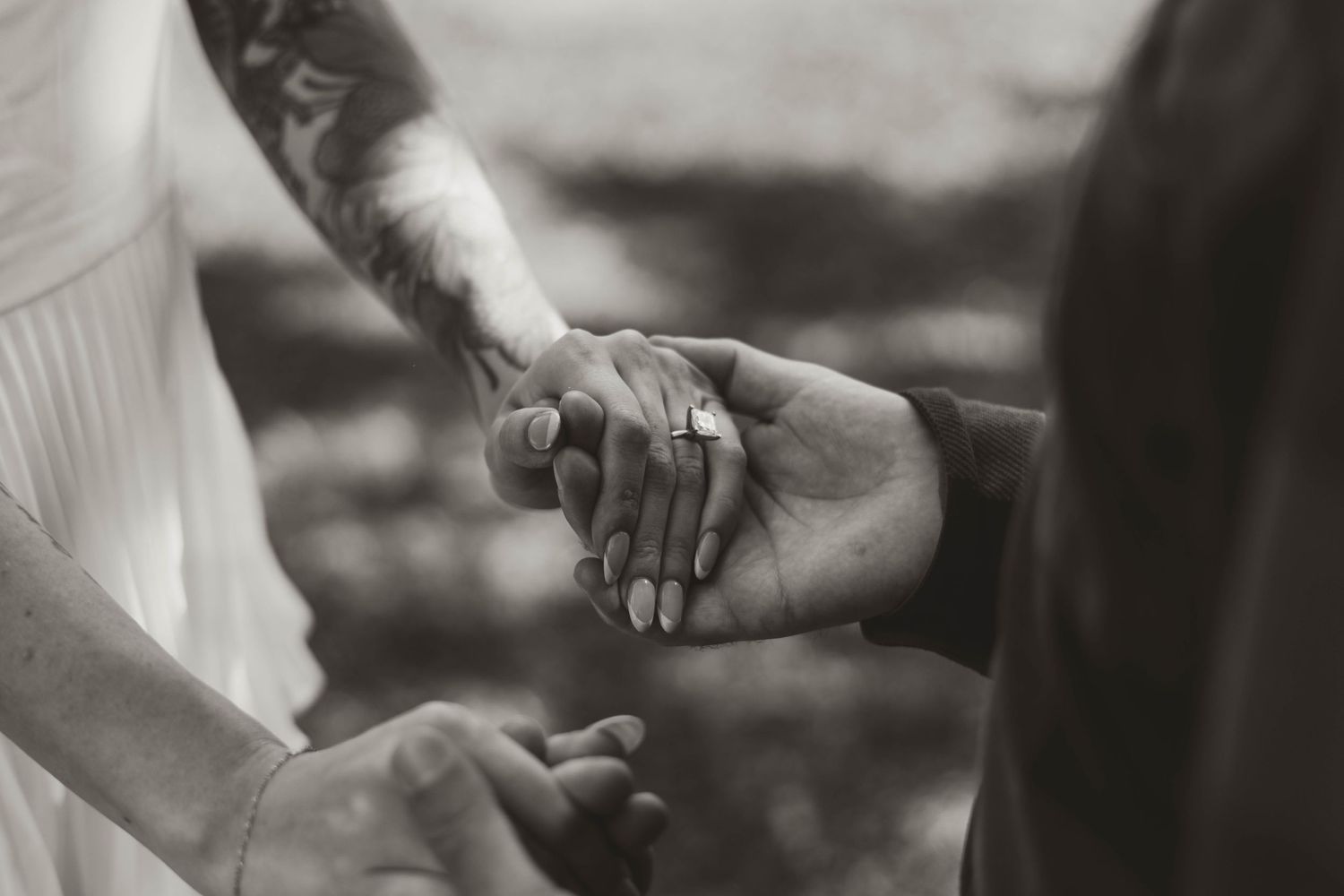 Two hands tenderly clasping together in an intimate black and white moment.