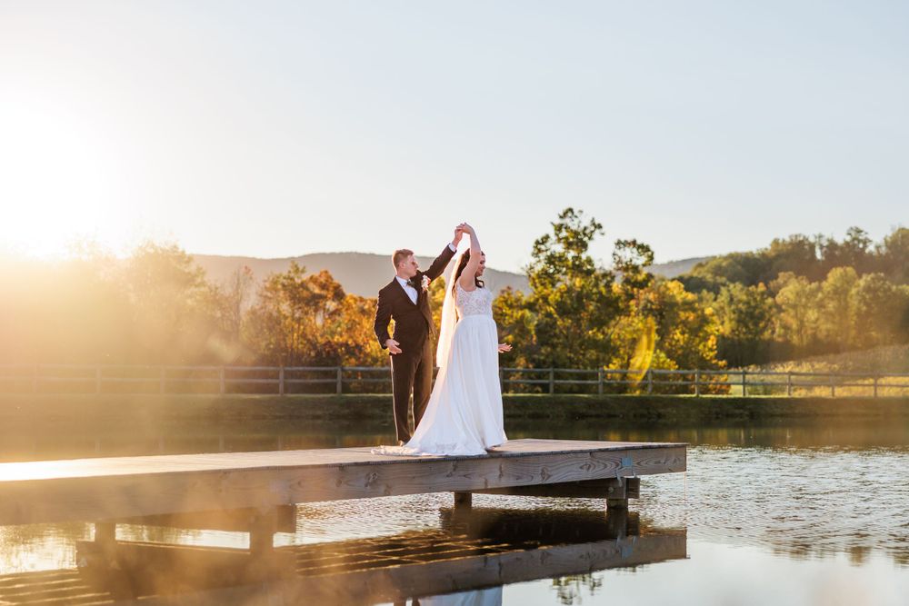 Newlyweds share a romantic moment on a dock during golden hour sunset.
