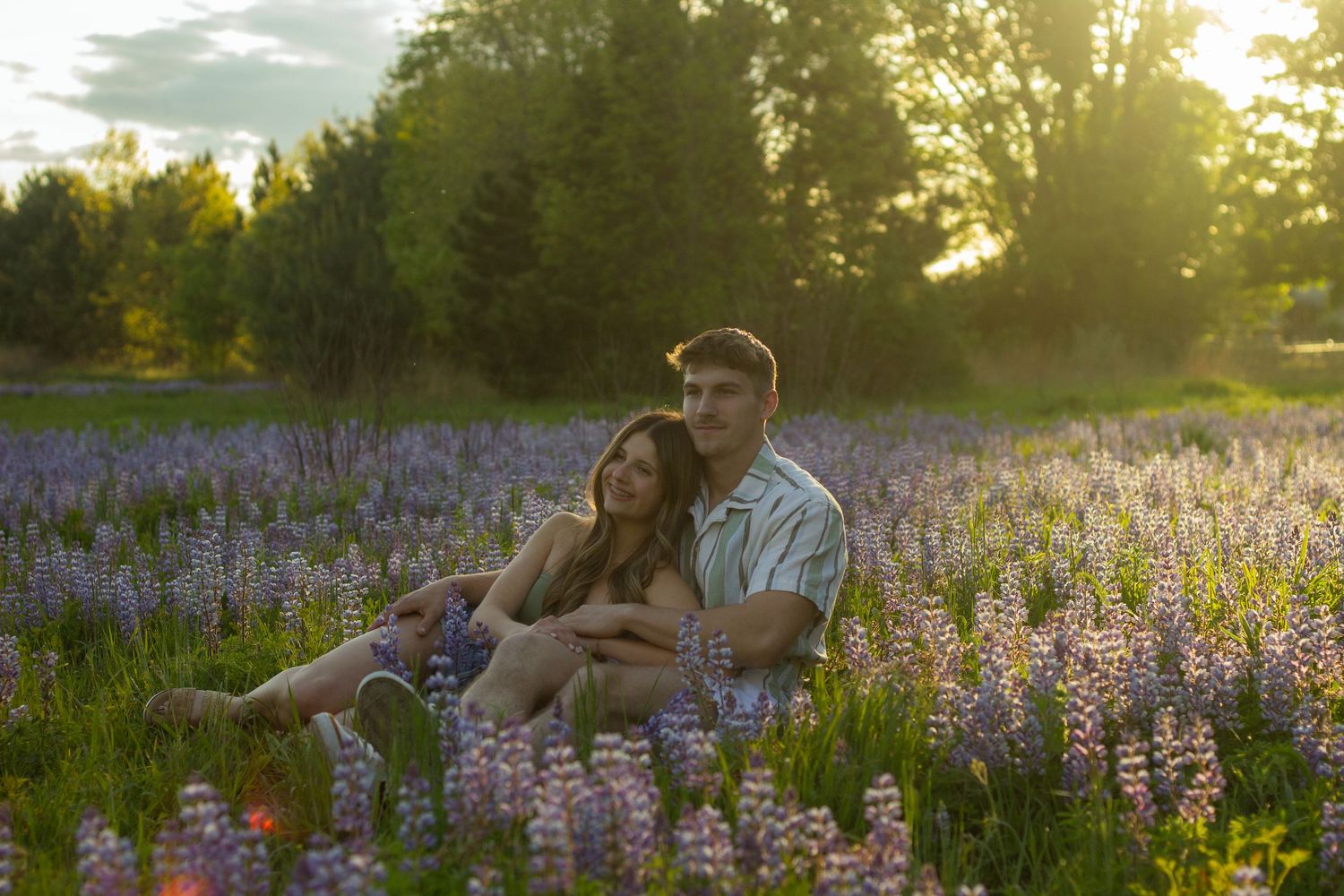 A couple lays in a flower field during their engagement photos in a park in Flushing, Michigan.