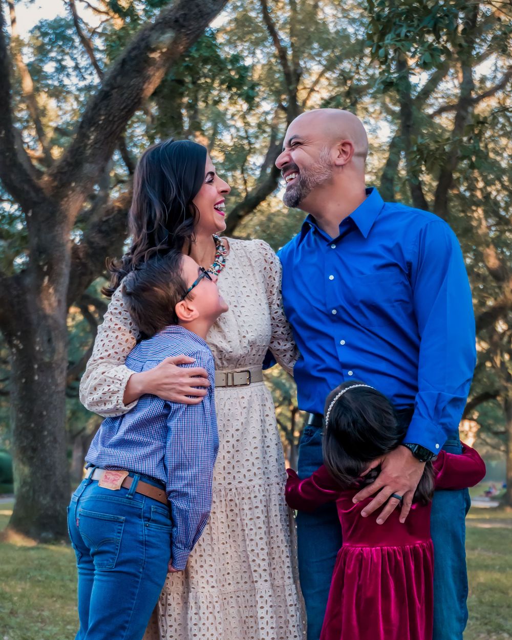 A couple in blue and white outfits share romantic moments in a park setting with trees in the background.