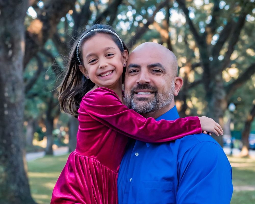 A parent and child in matching blue and pink outfits share joyful moments together in a park setting.