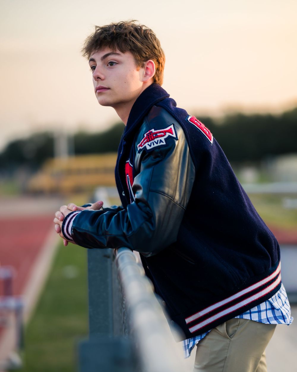 A person in a navy jacket leans against a railing at dusk, creating a contemplative silhouette against the fading light.