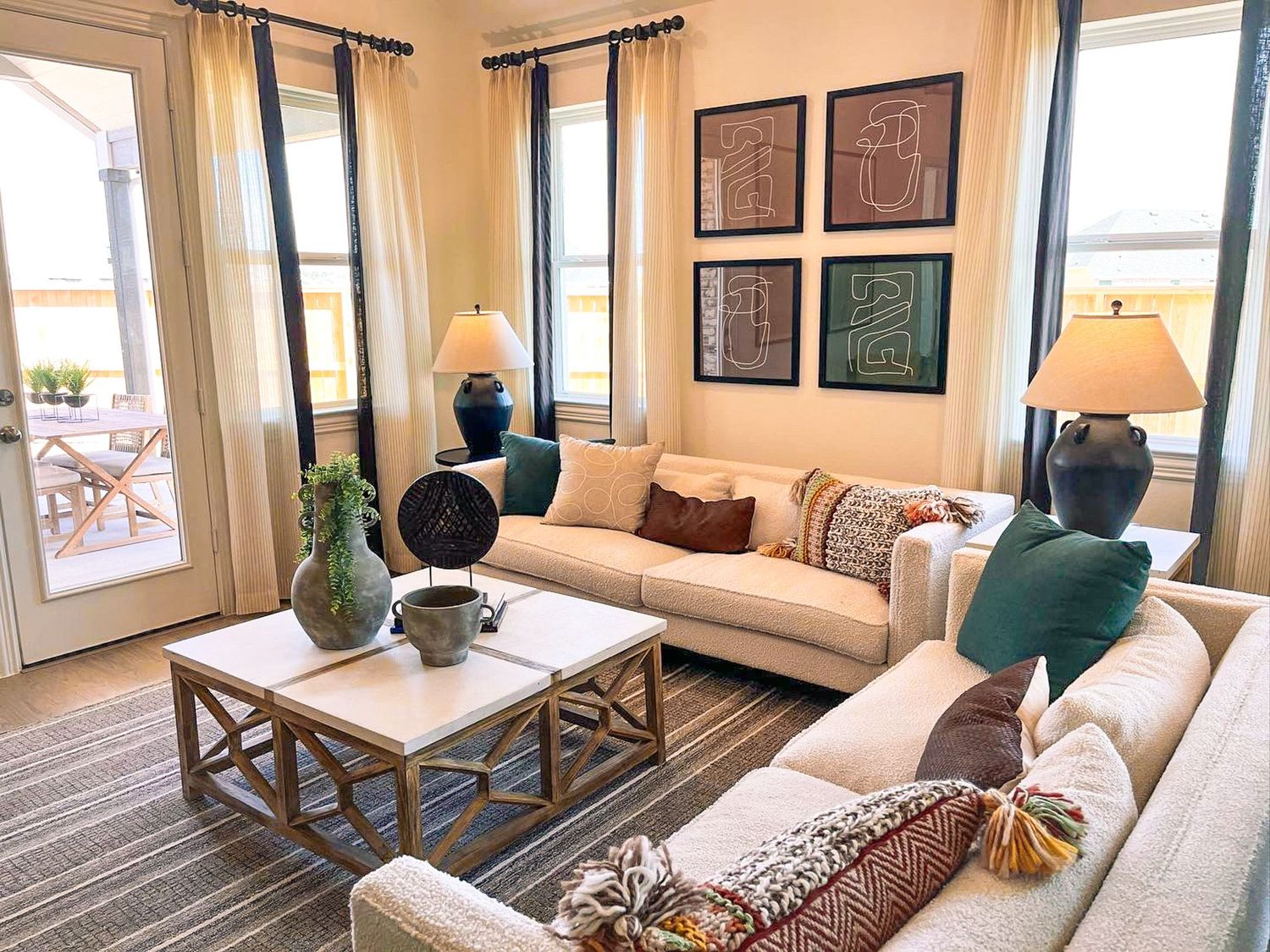 Modern living room interior with beige walls, large windows and comfortable seating arrangements.