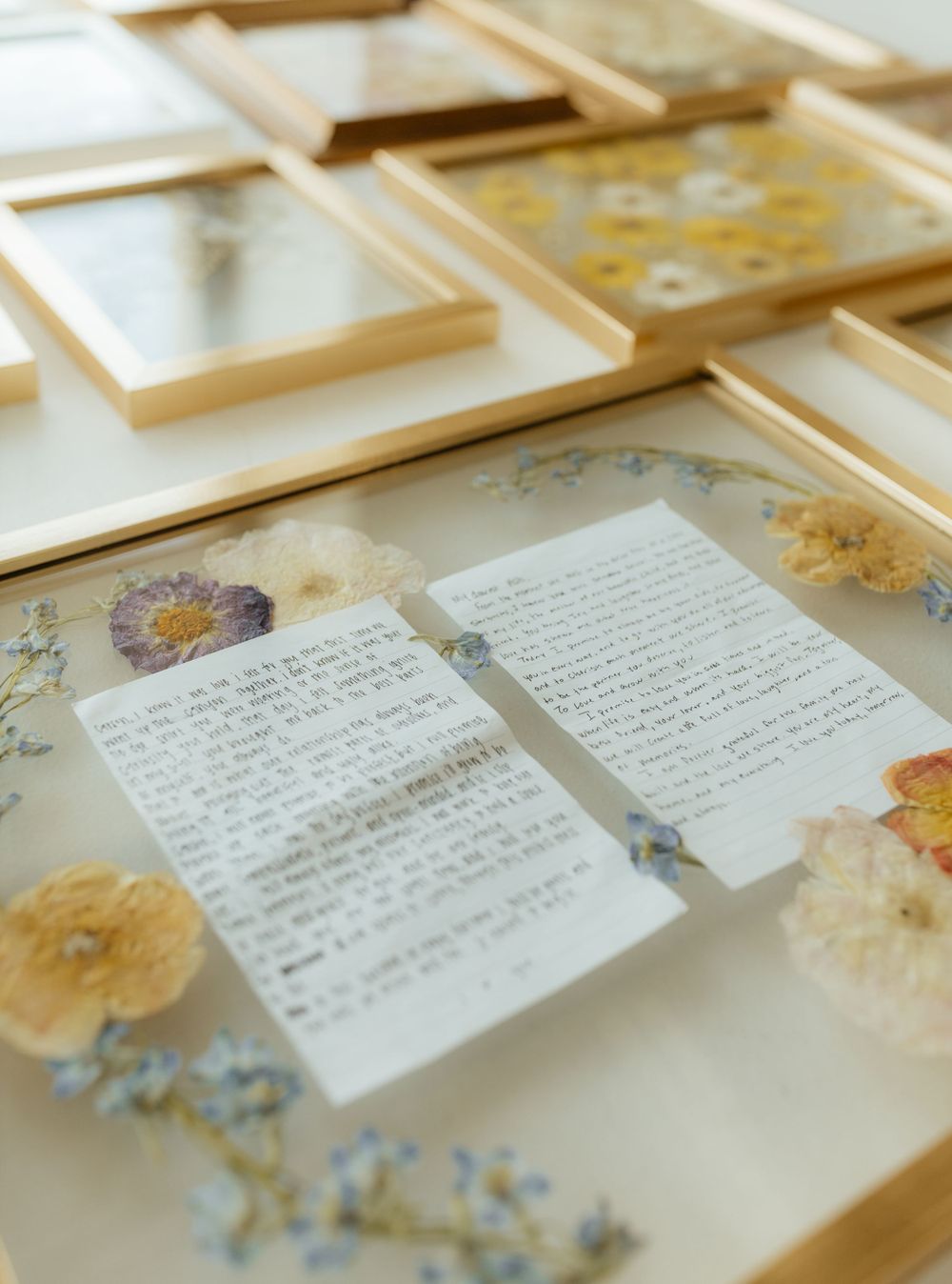 Wooden frames with pressed flowers and handwritten notes displayed on a light surface.