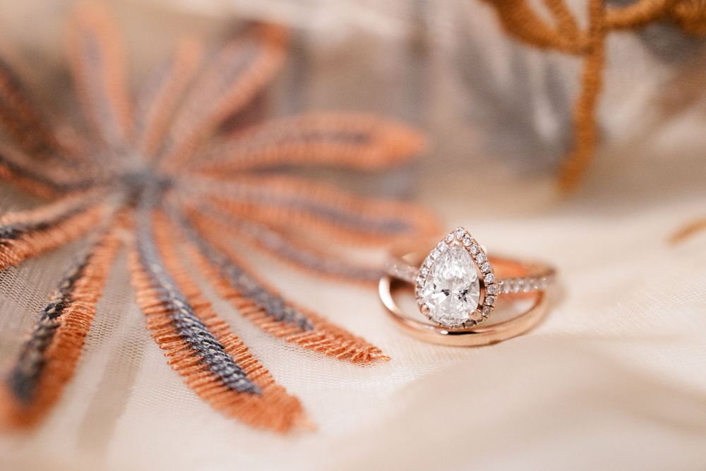 Close-up of an elegant diamond engagement ring on delicate floral patterned fabric.
