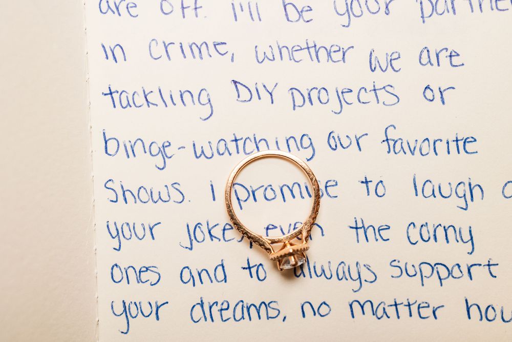 Engagement ring photographed on handwritten wedding vows with romantic message.