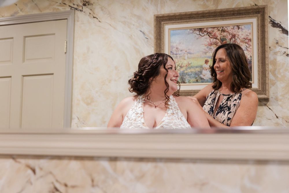 Two women share a joyful moment in an elegant room with cream-colored walls.
