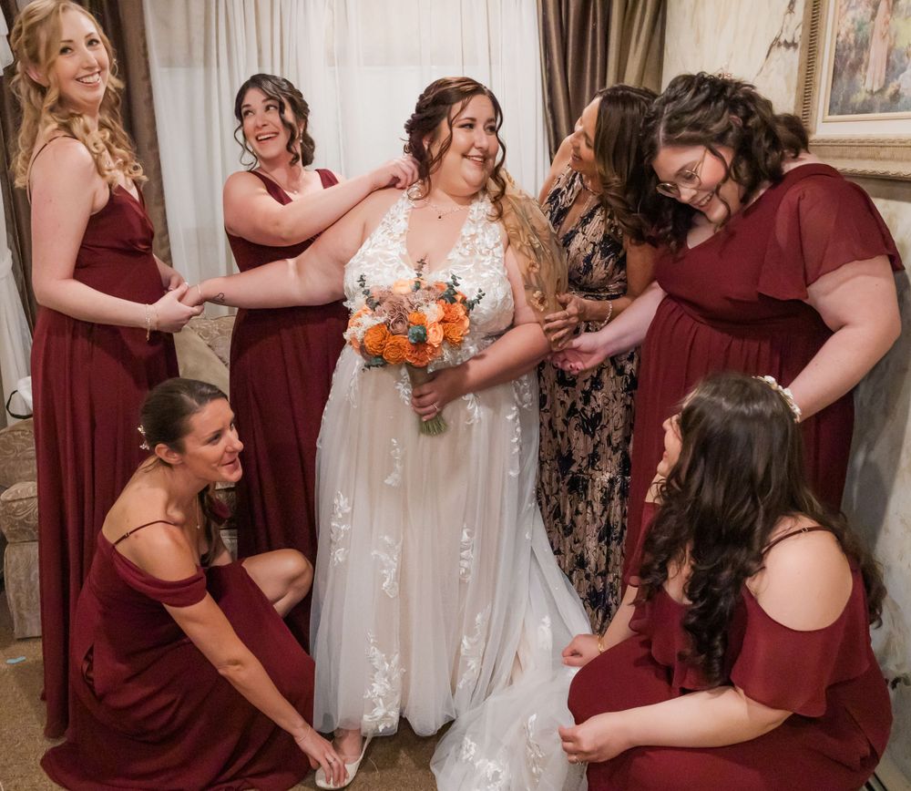 Wedding party in burgundy dresses gather around during preparation moments.