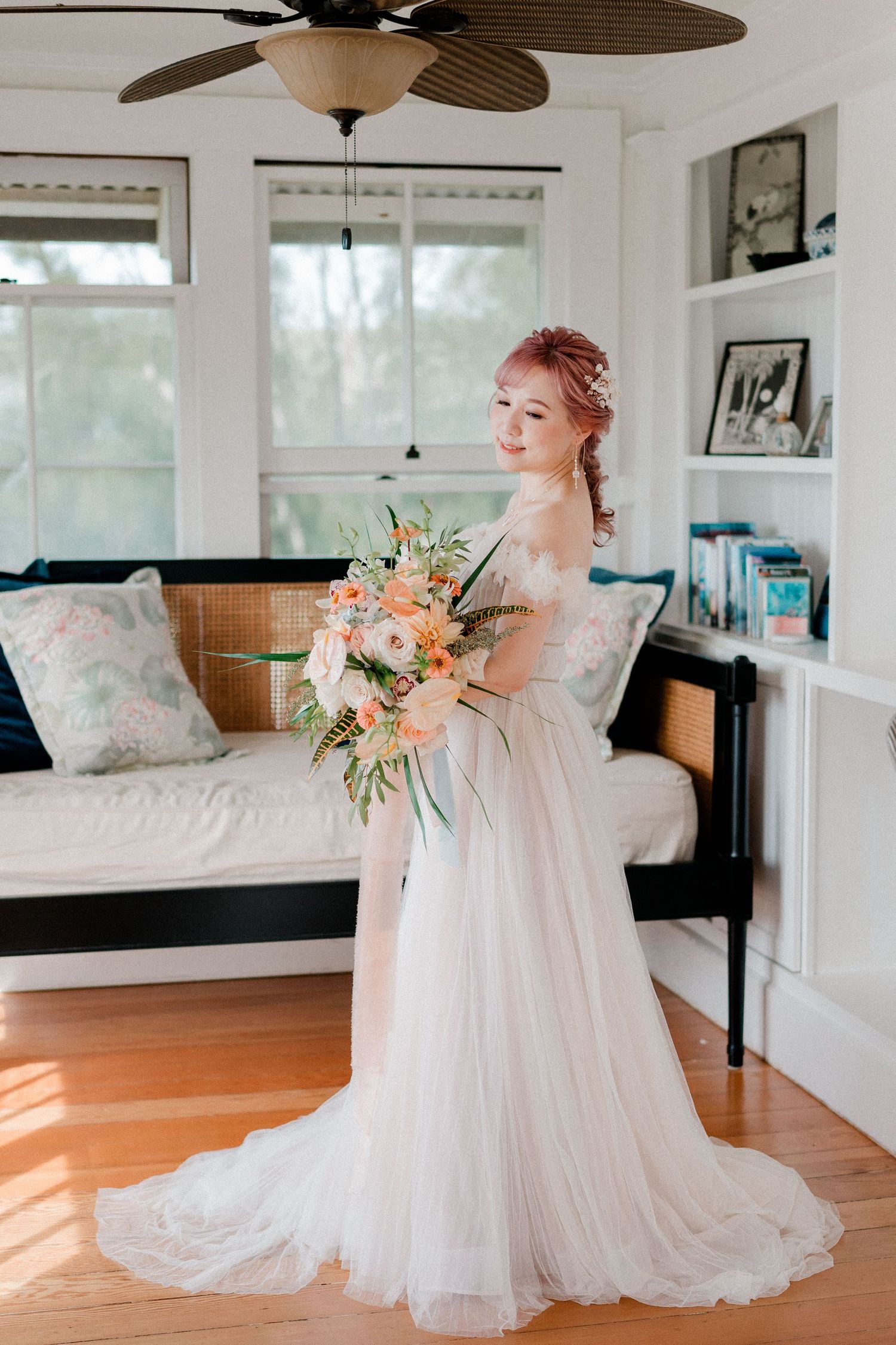 Elegant bridal portraits in white flowing gown inside sunlit room with ceiling fan.