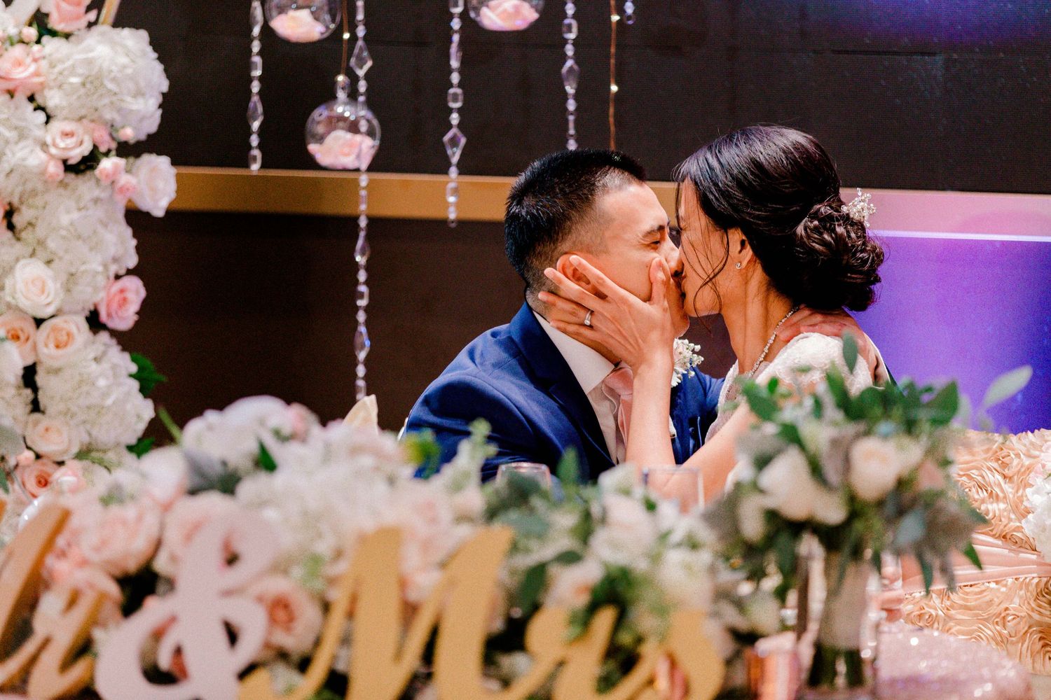 Romantic wedding reception with crystal chandeliers and soft pink floral arrangements.