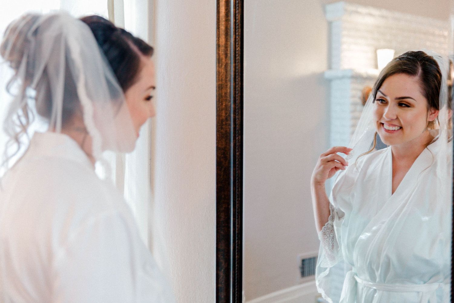 Getting ready on wedding morning with reflections in mirror wearing white robes.