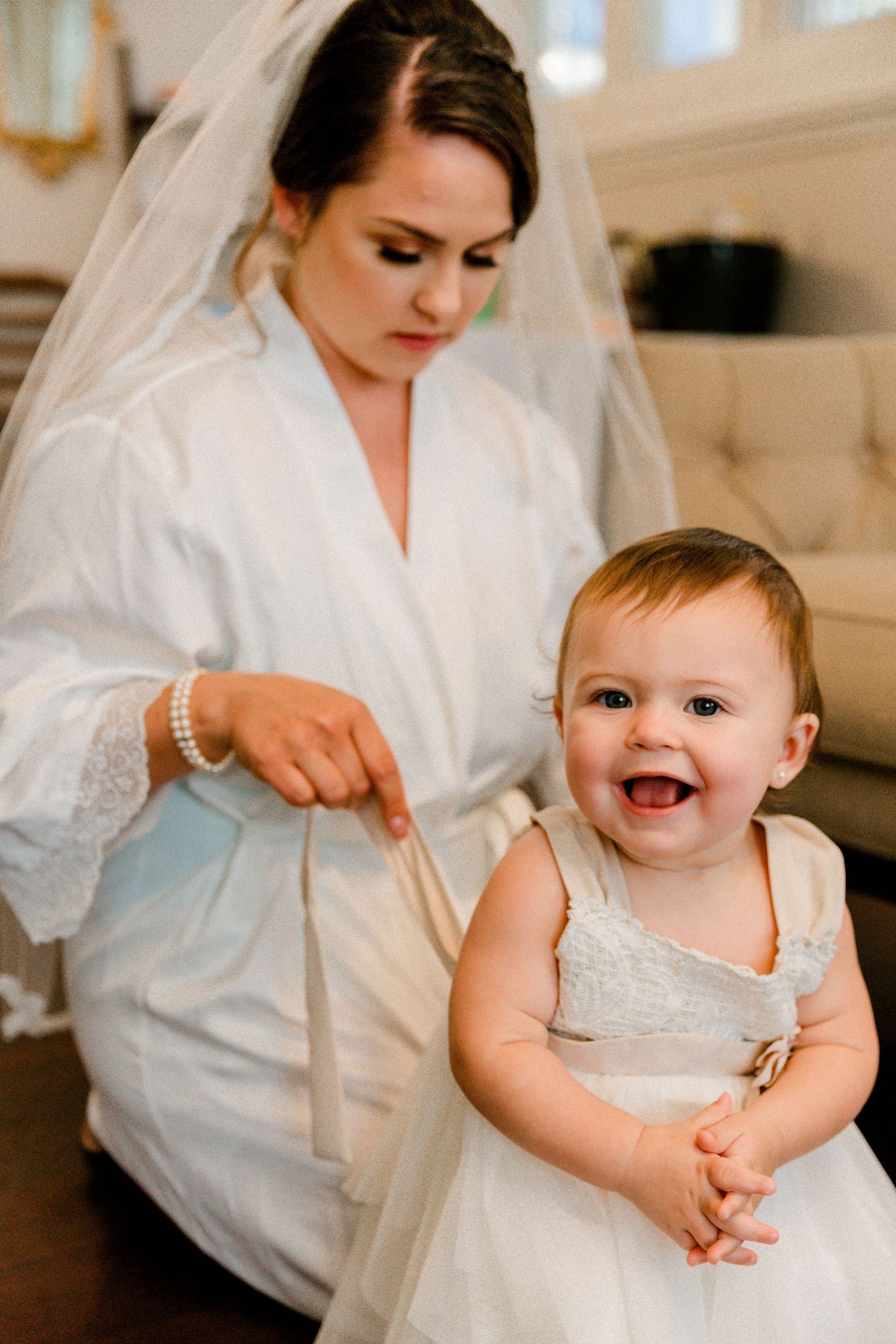 A heartwarming pre-wedding moment with a smiling baby in white dress.