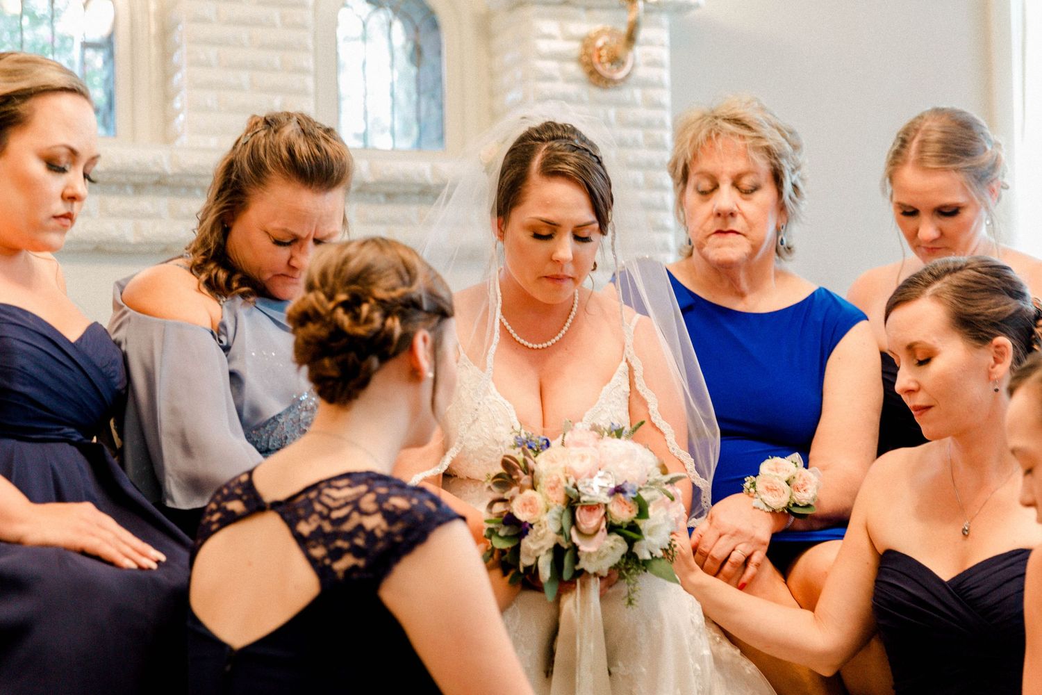 A bridal party gathers in an intimate moment inside a church.