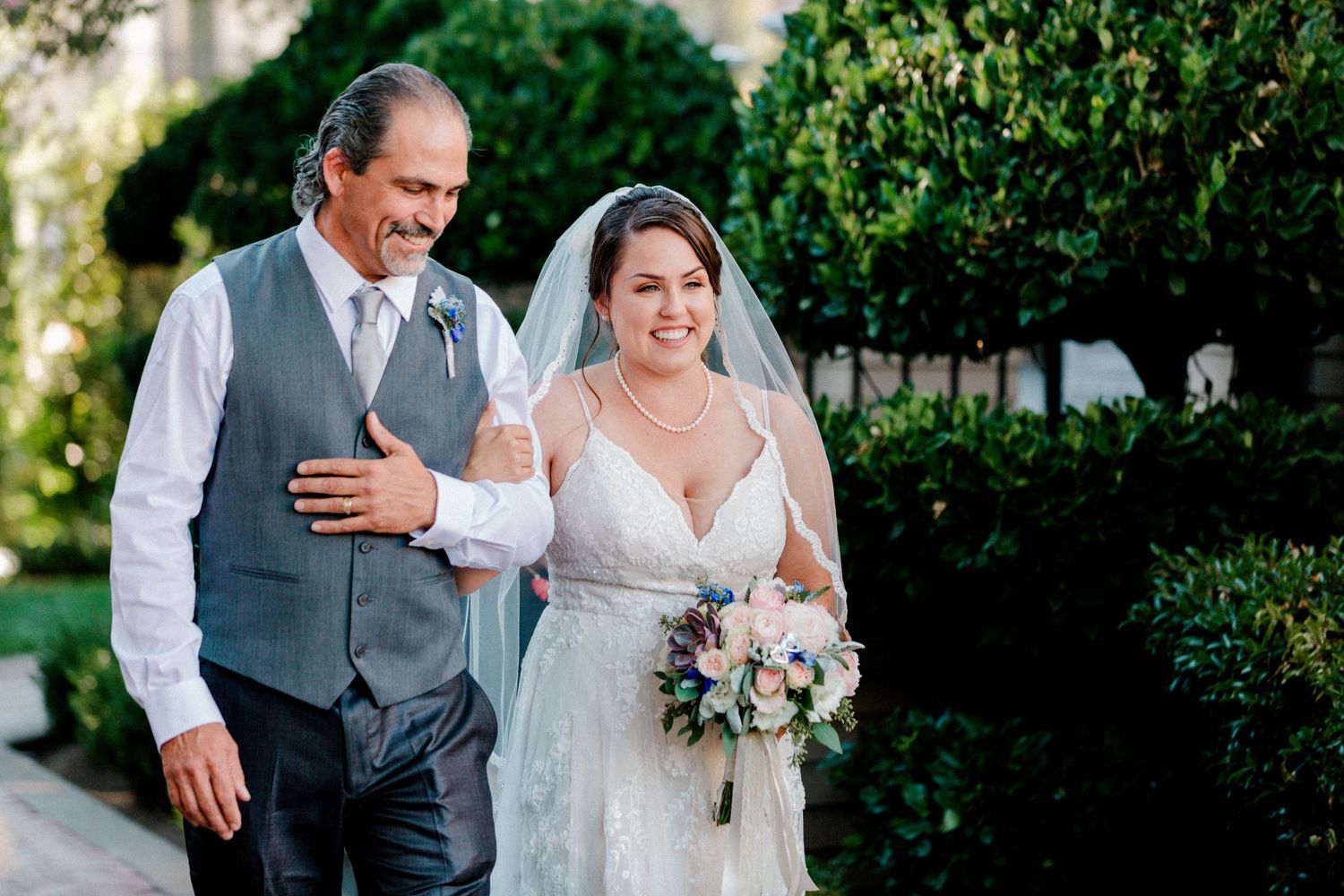 A touching outdoor wedding moment captured in a garden setting with bouquet.