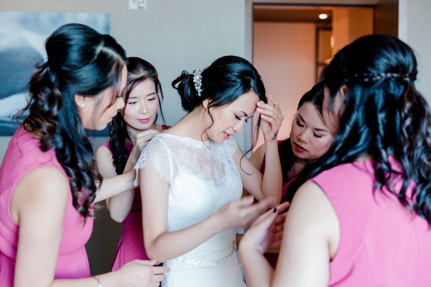 A tender moment shared between bridesmaids in pink dresses during wedding preparations.