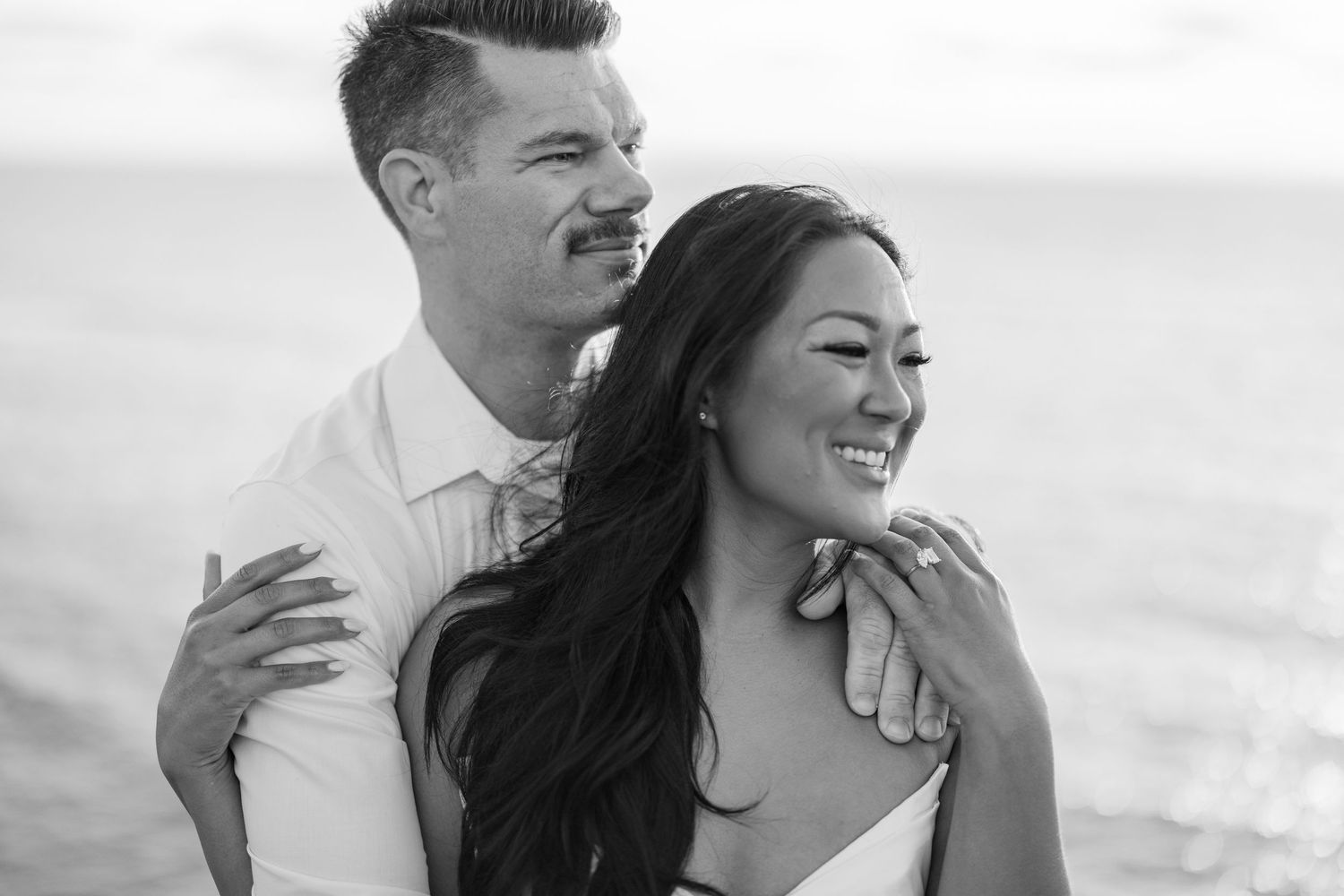 A joyful black and white portrait of a couple by the sea.