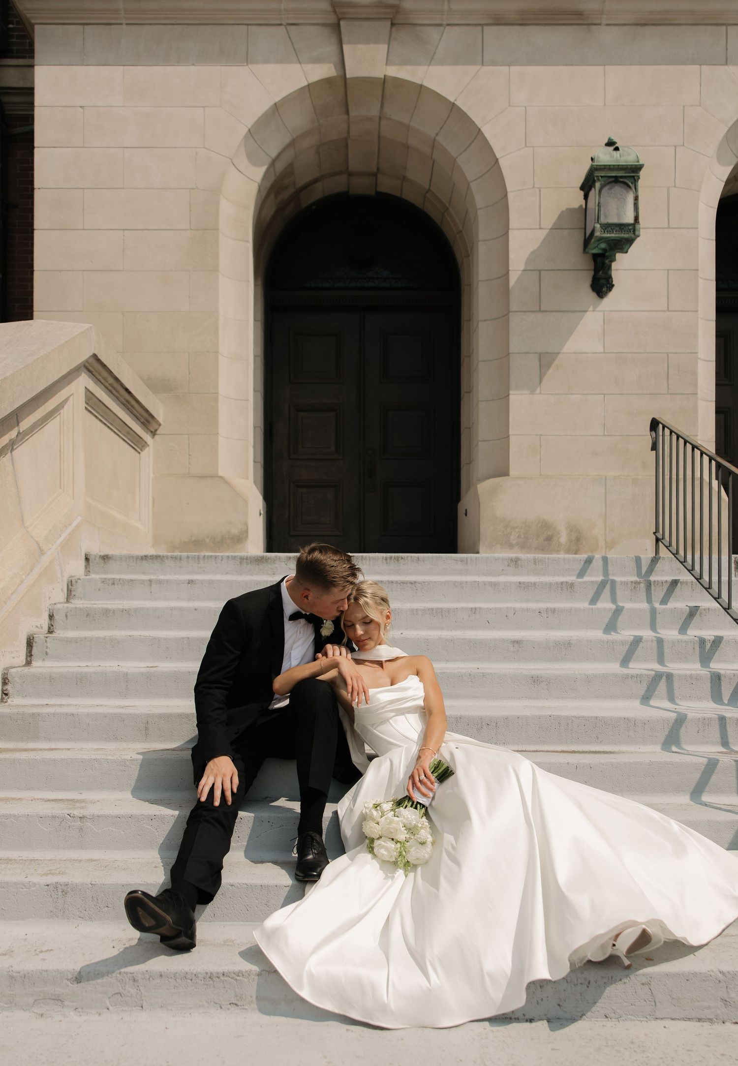 A romantic black and white wedding photo showing a tender moment between newlyweds under a flowing veil.