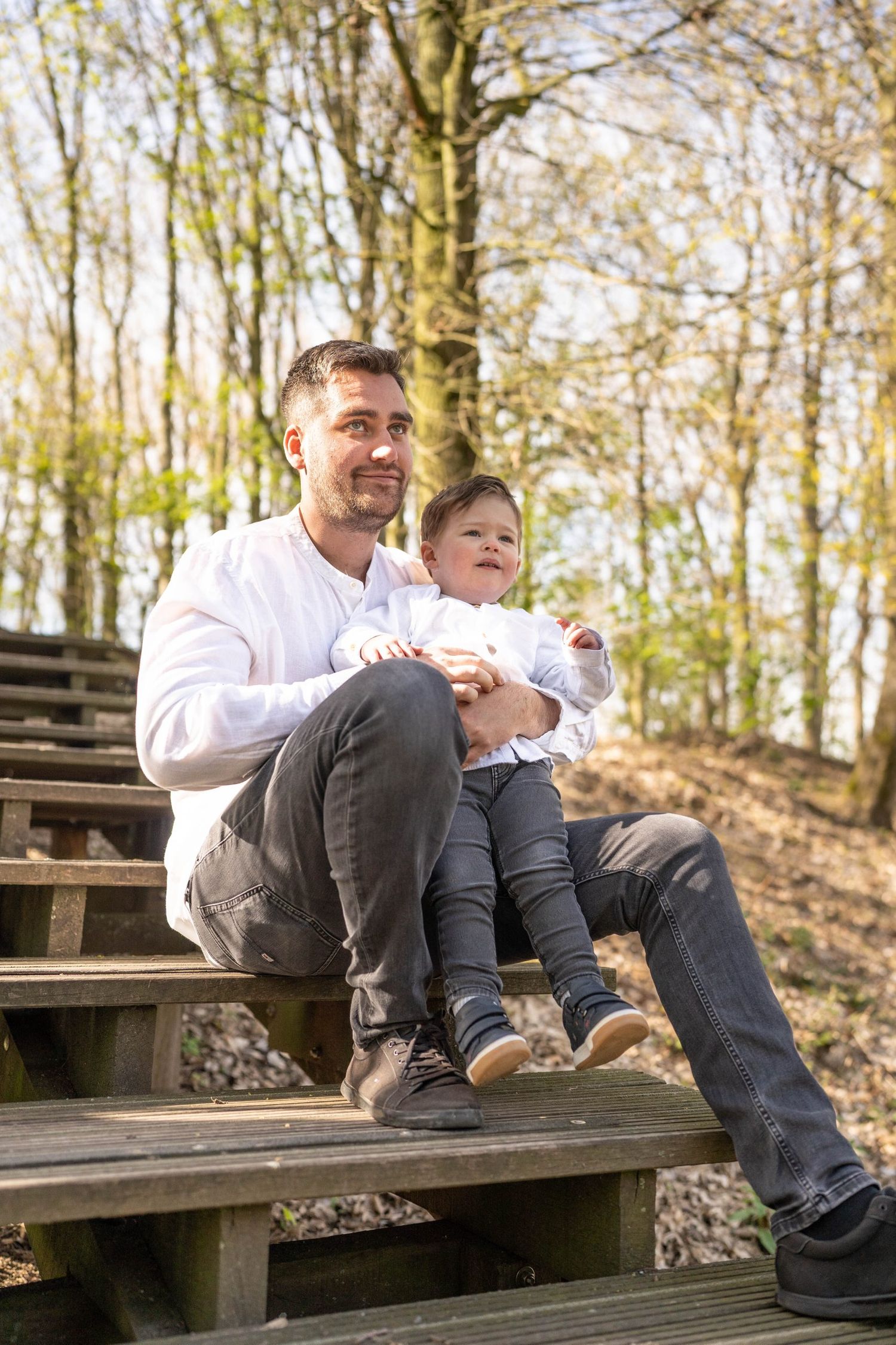 Father and child sharing special moment while sitting on wooden stairs in forest.