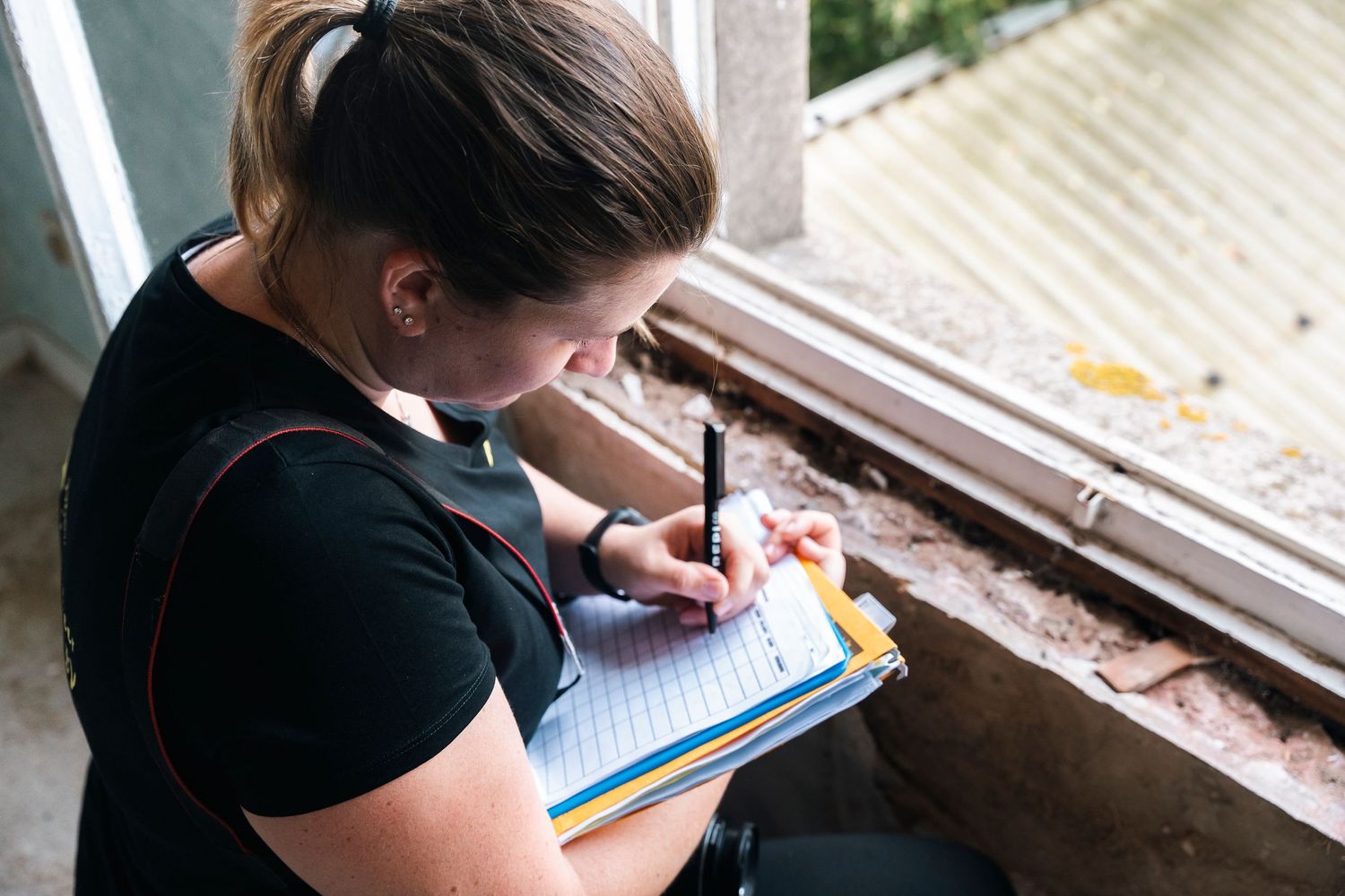 Investigator making notes on clipboard during field examination.