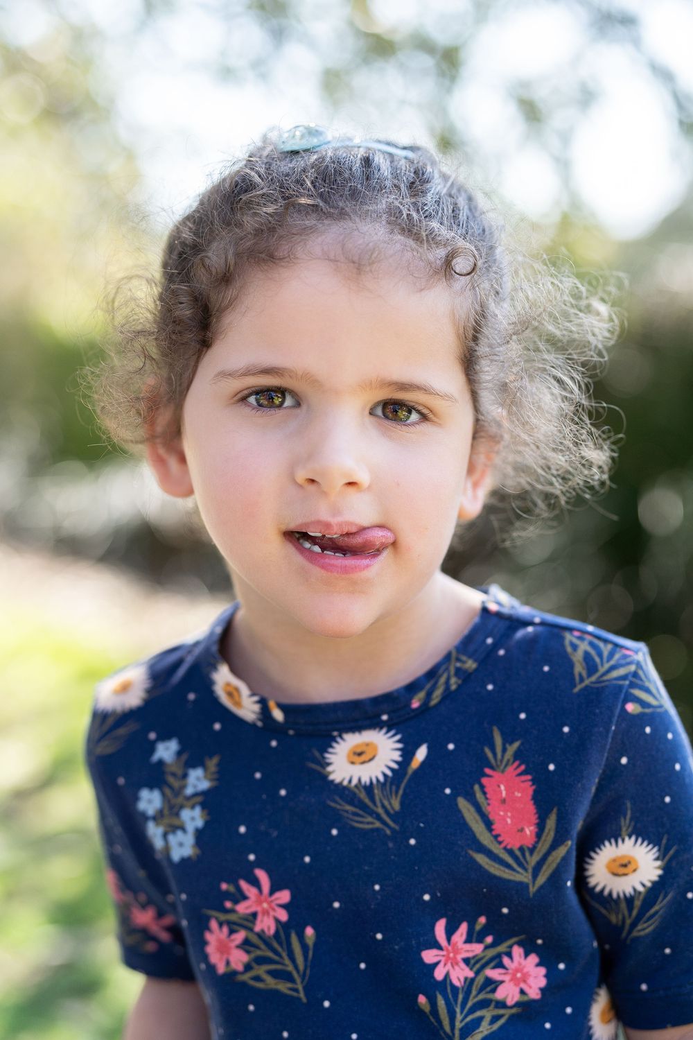 Artistic portrait of a child in beautiful soft flattering light with her tongue out at an outdoor popup in Perth
