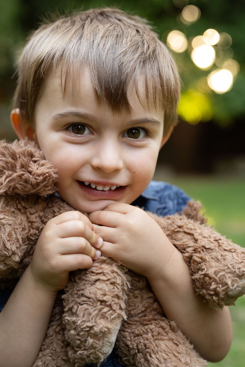 Portrait of a young boy in golden light at an outdoor sunset family photography session in Perth holding a stuffed toy