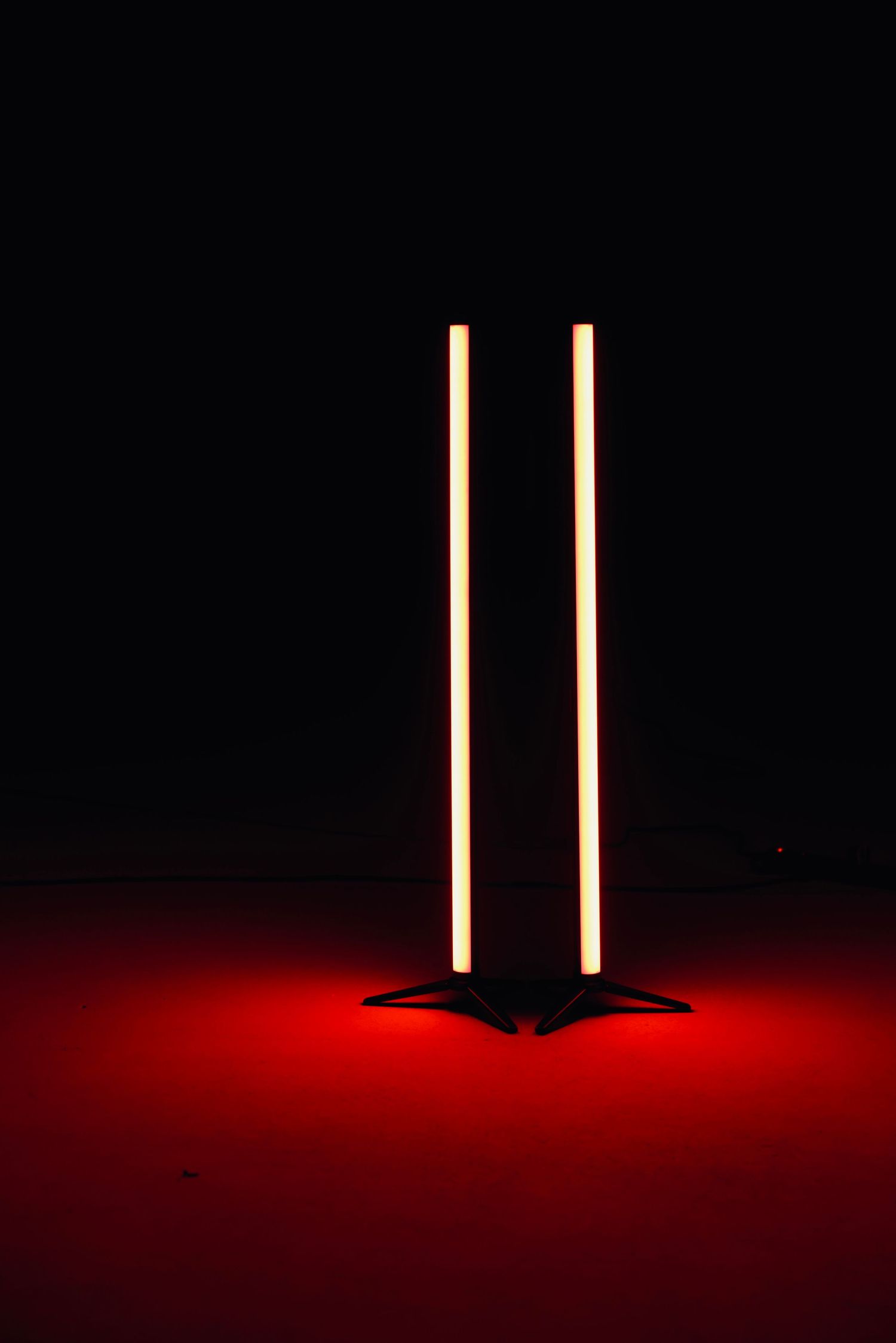 Two vertical light beams glowing against dark red background.