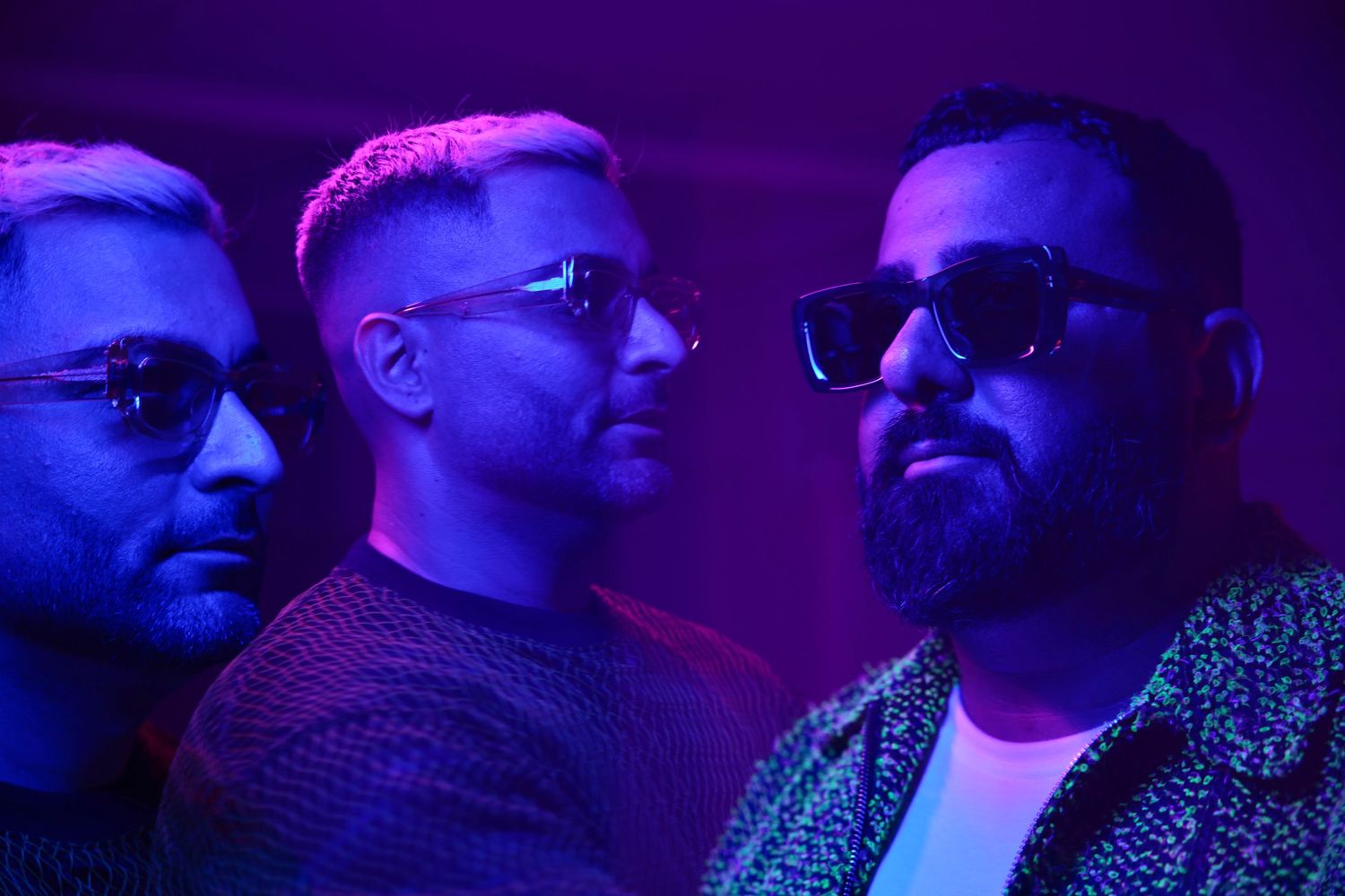 Side profile of people wearing sunglasses illuminated by purple and blue lighting effects.