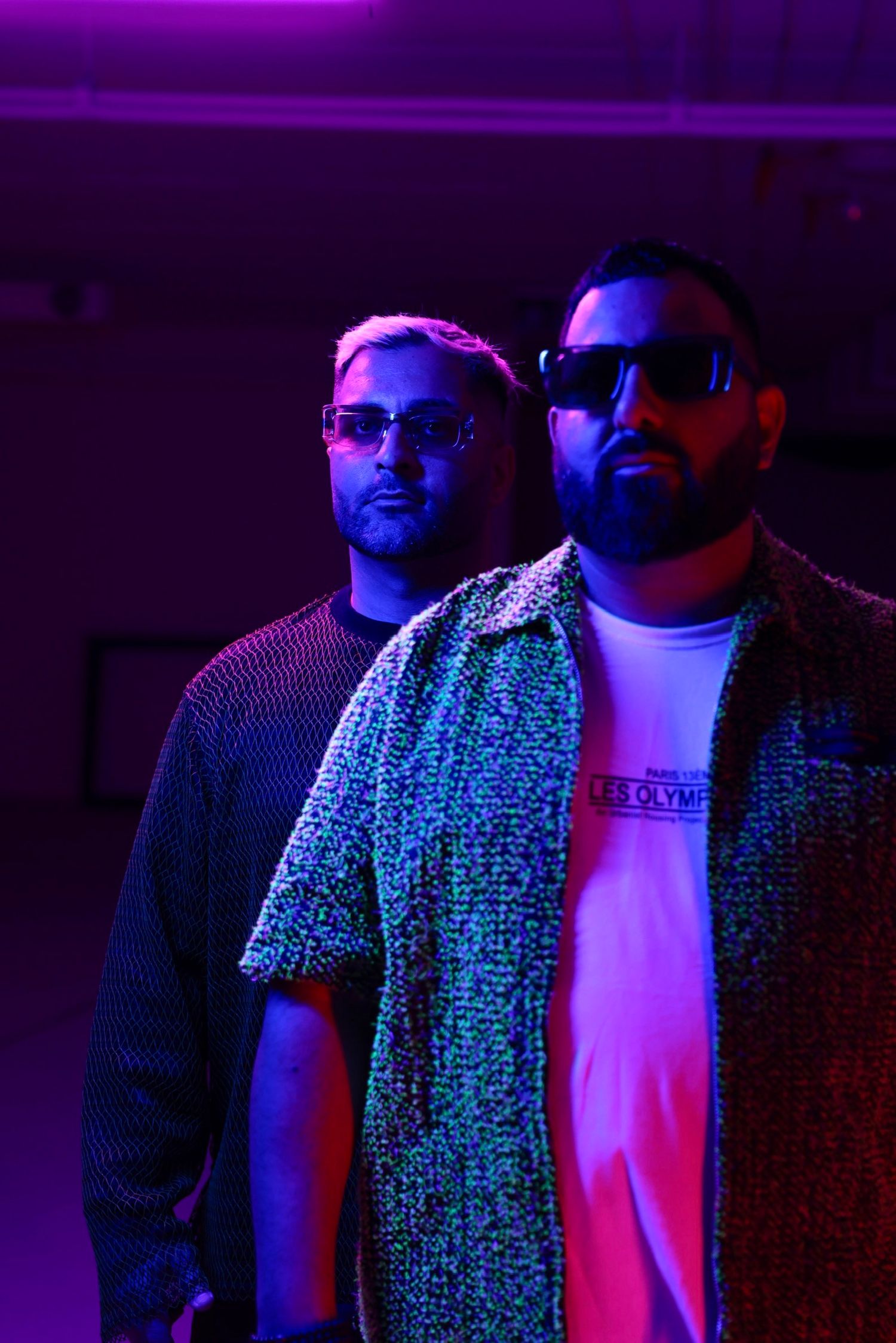 Group shot with people wearing casual attire under vibrant purple neon lighting.