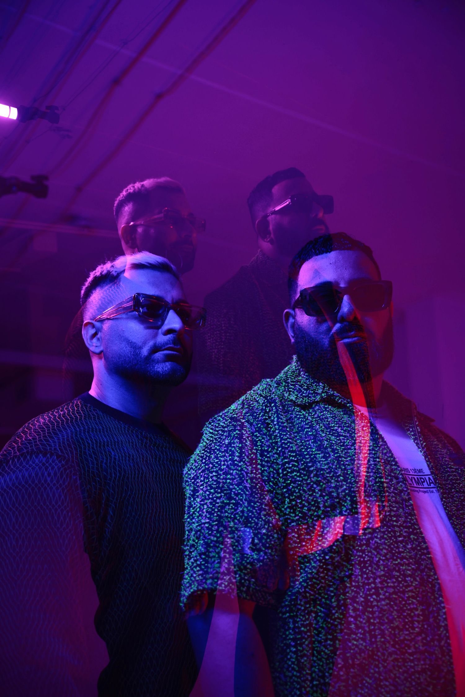 Group photo with people wearing sunglasses under intense purple lighting.