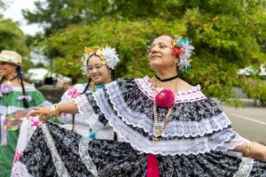 Traditional dancers in flowing black and white pollera dresses perform at an outdoor cultural festival.